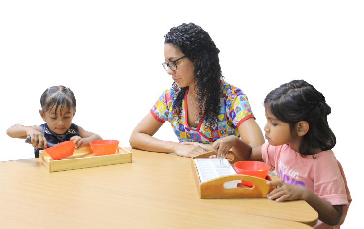 Educadora sentada en una mesa con dos niñas
